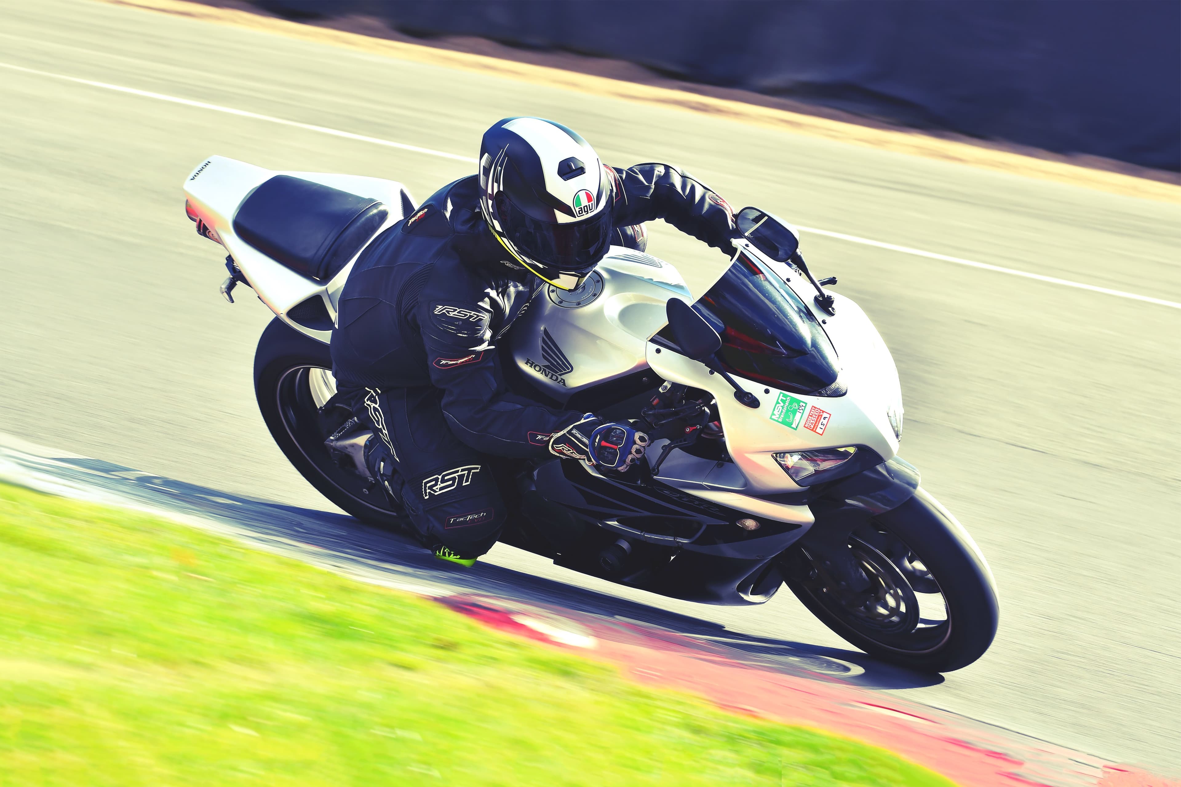 Rider in leathers cornering a sportsbike on a race track