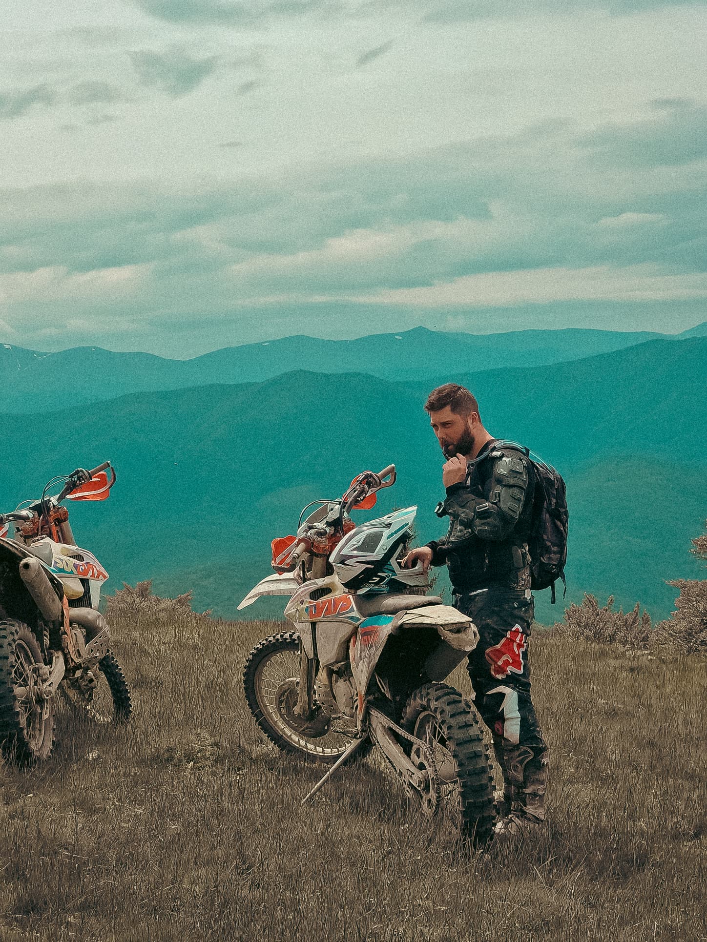 Tom on a KTM enduro bike with mountain valley in the background